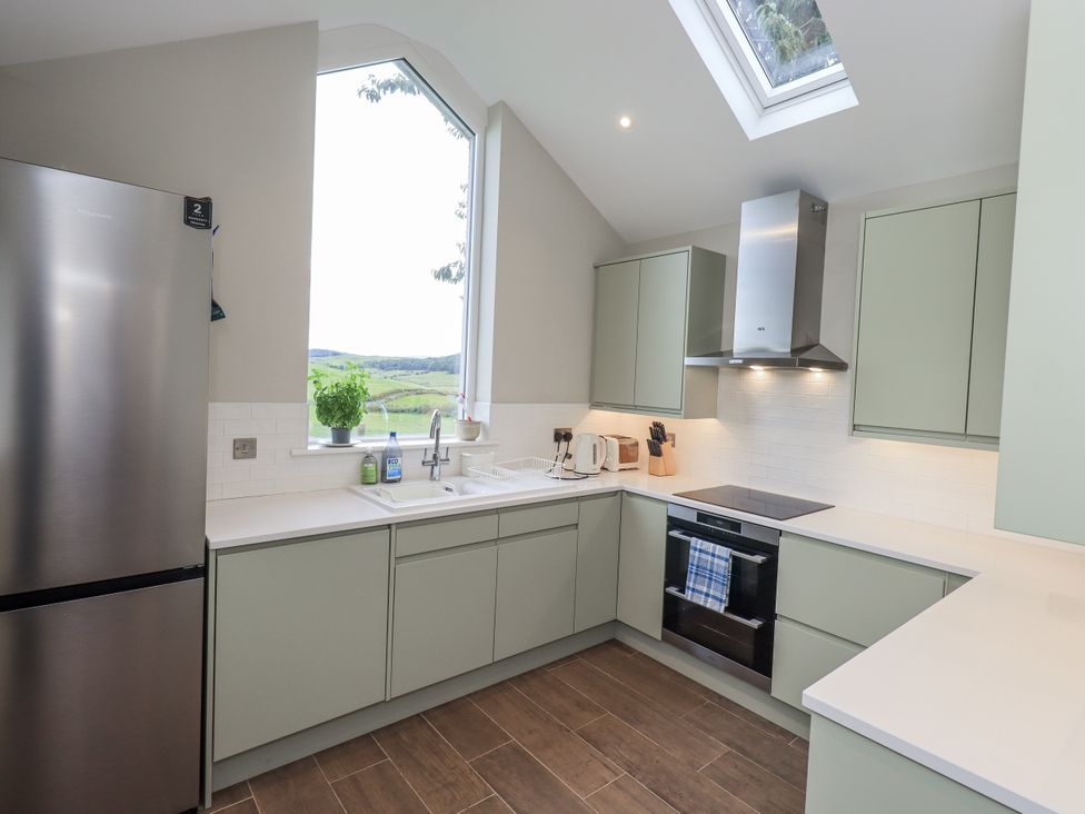 A kitchen with a refrigerator, sink, and oven at The Old Cottage in Oxen Park near Ulverston