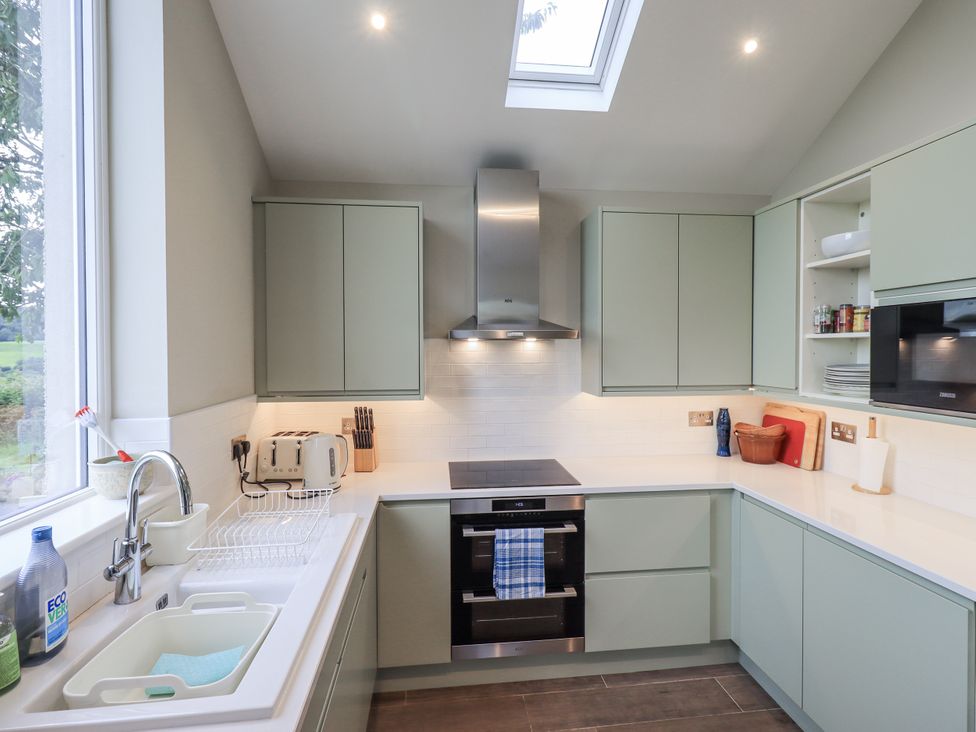 A kitchen with green cabinets and modern appliances at The Old Cottage in Oxen Park near Ulverston