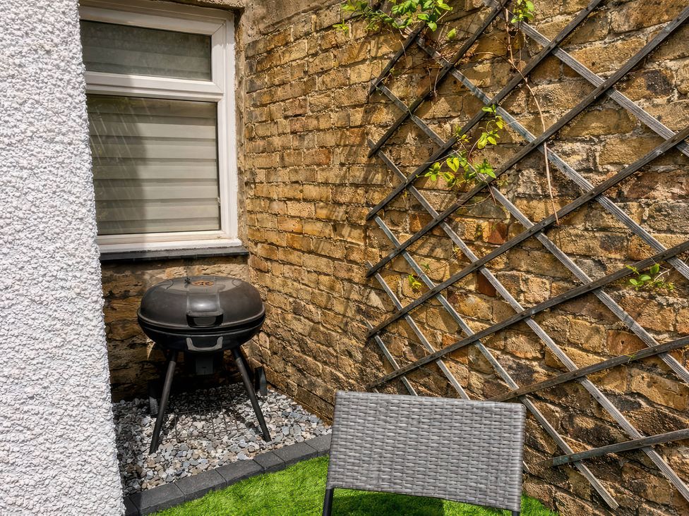 A patio area with a grill and a chair at Number Ten in Amble