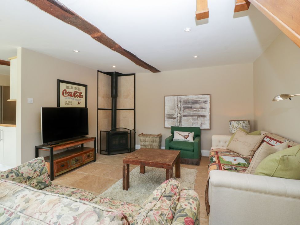 A living room with a television and a coffee table at Stable Cottage in Broadway