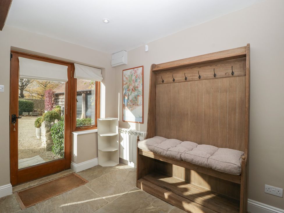 A hallway with a wooden bench and hooks at Stable Cottage in Broadway