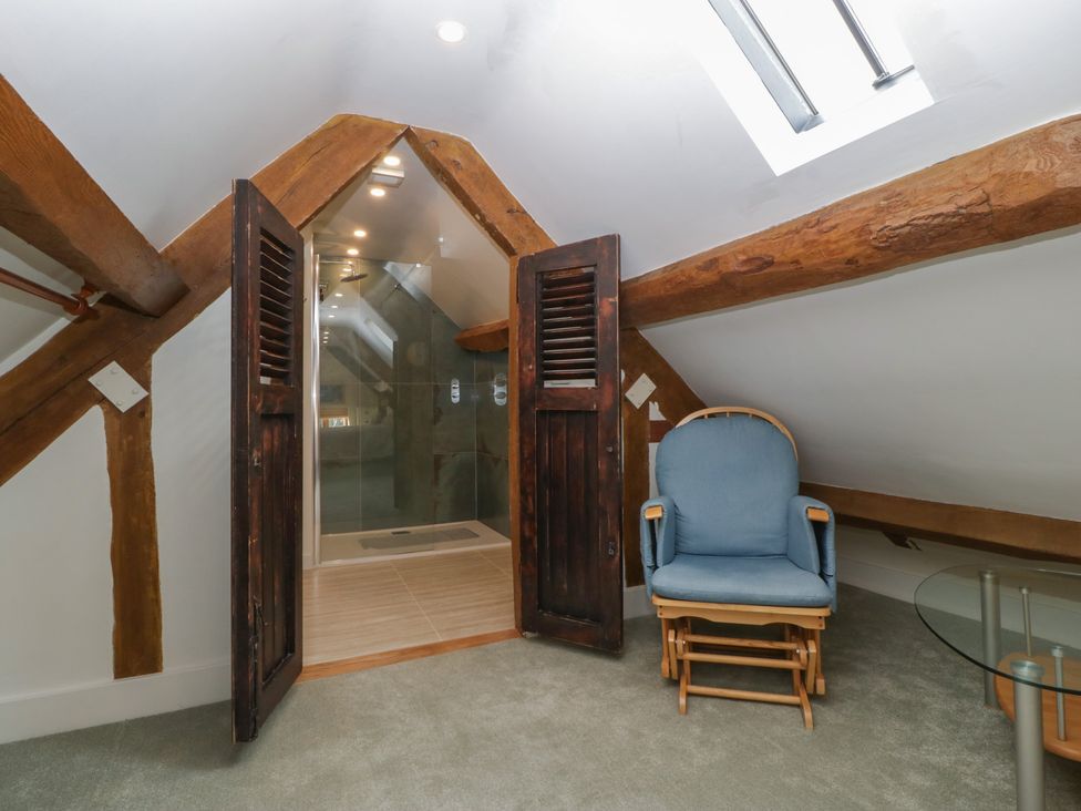 A bathroom with a shower and armchair at Stable Cottage in Broadway