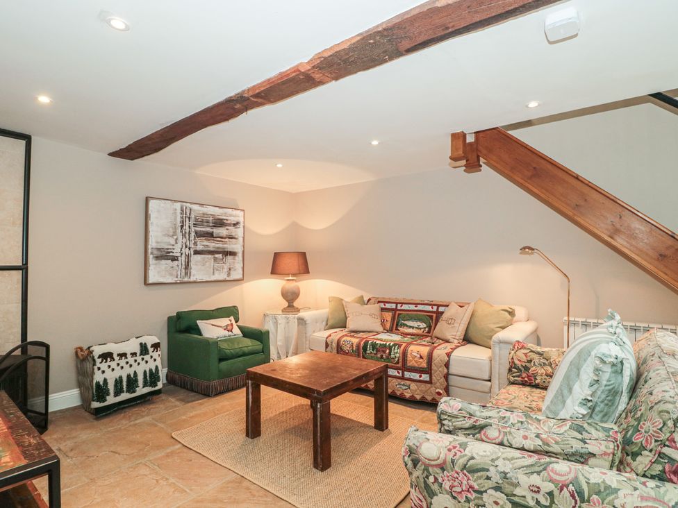 A living room with a green armchair and a coffee table at Stable Cottage in Saintbury near Broadway