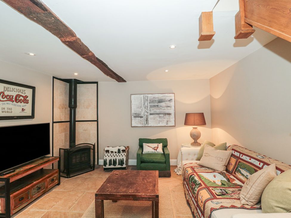 A living room with a couch, coffee table, and fireplace at Stable Cottage in Saintbury near Broadway