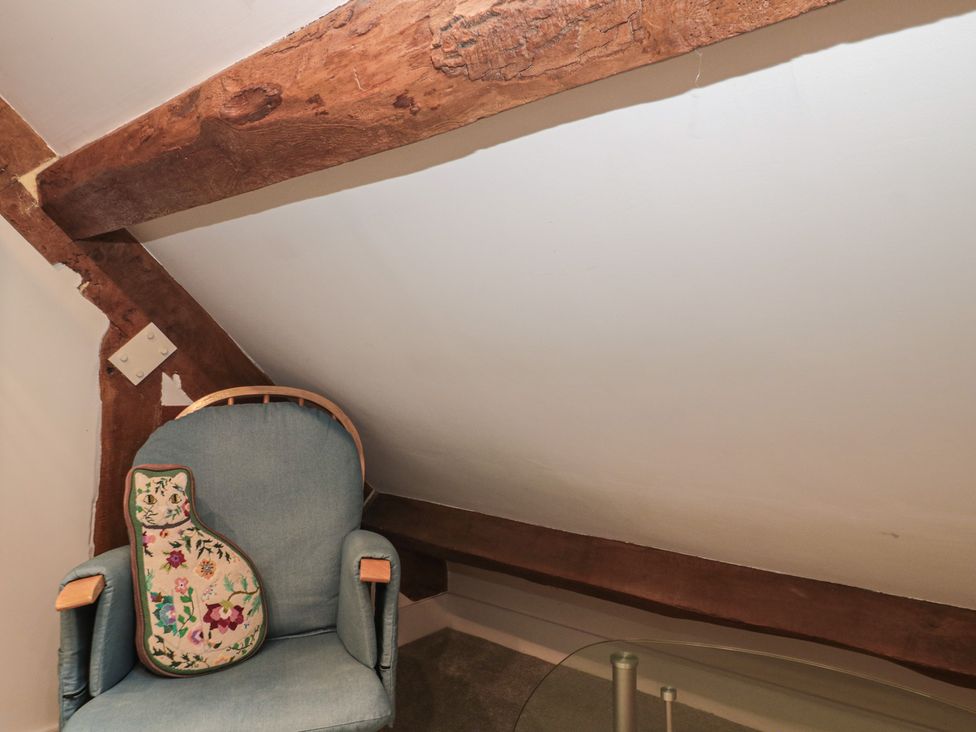 An attic with a chair and a cushion at Stable Cottage in Saintbury near Broadway