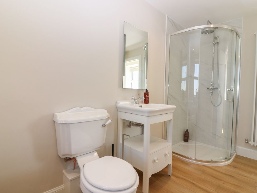 A bathroom with a toilet, sink, shower, and mirror at No 4 - 3 bed in Haddington