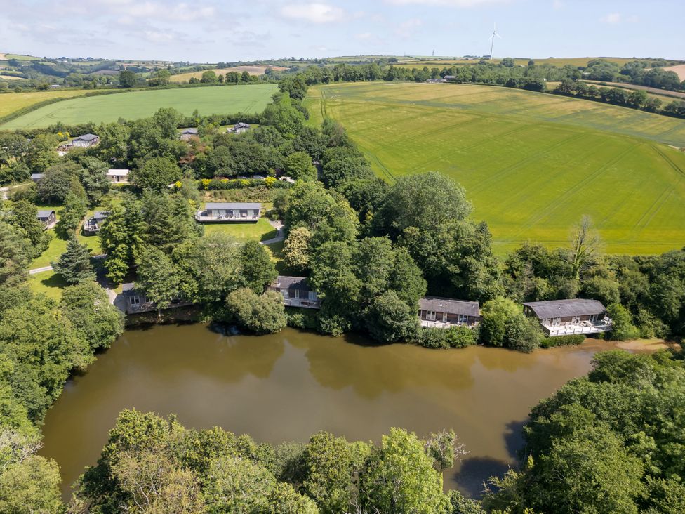 A view of houses surrounded by trees near a body of water at 3 Hedgerows in Lanreath