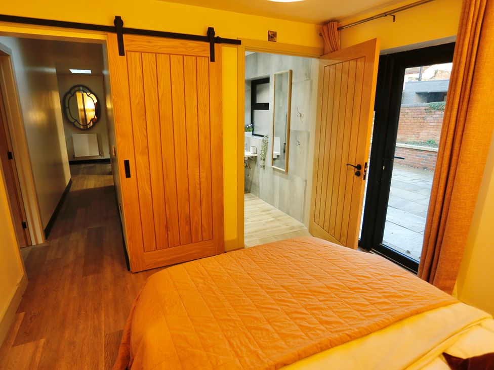 A bedroom with a bed and open doors leading to a bathroom and hallway at Havendale, Chesterfield