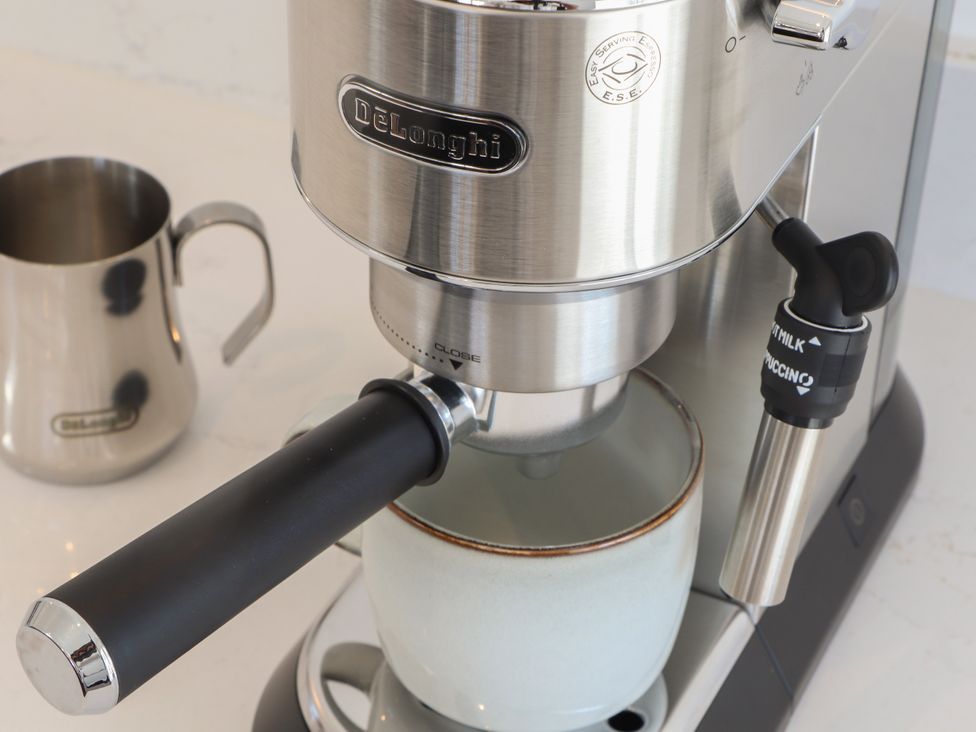 An espresso machine with a coffee cup and milk jug at Little Victory in Pendeen
