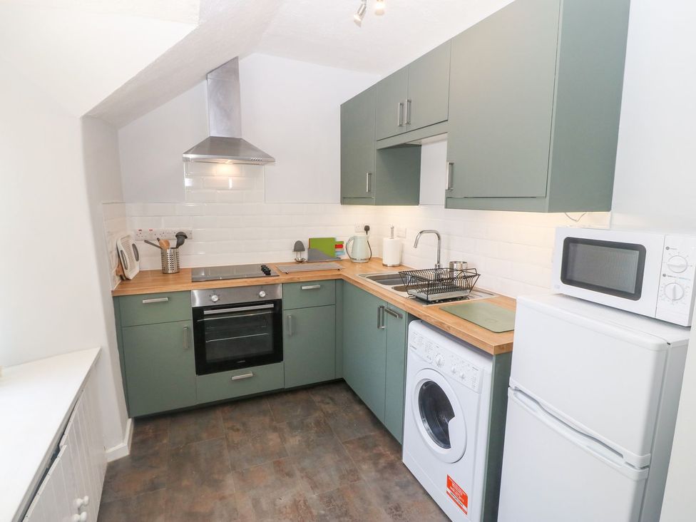 A kitchen with green cabinets wooden countertops white appliances and a stainless steel oven at Medical Hall in Cemaes Bay