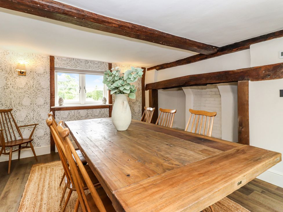 A dining room with a large wooden table and chairs at Tuffs Farm Cottage 1 in Kings Langley