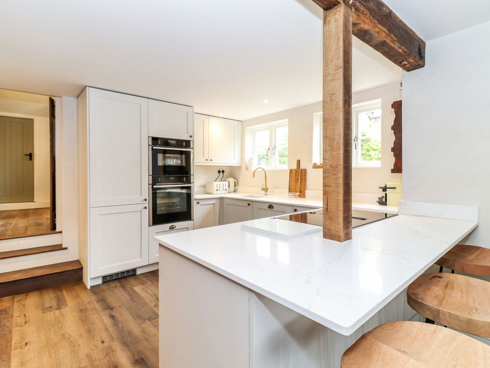 A kitchen with bar stools and cabinets at Tuffs Farm Cottage 1 Kings Langley