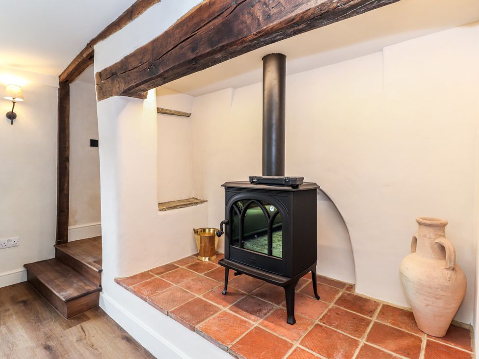 A living room with a wood stove and terracotta tiles at Tuffs Farm Cottage 1 Kings Langley