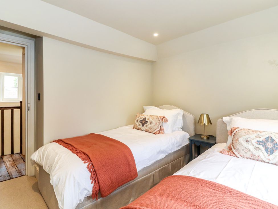 A bedroom with two beds and a bedside table at Tuffs Farm Cottage 1 in Kings Langley
