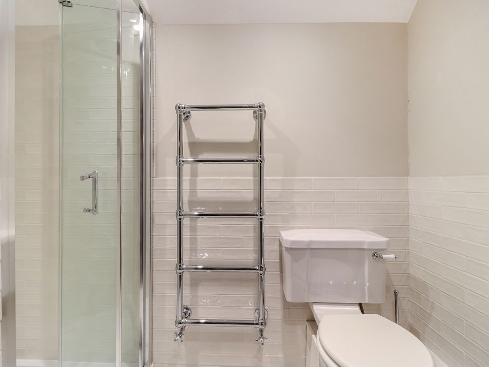 A bathroom with a shower, toilet, and towel rack at Tuffs Farm Cottage 1, Kings Langley
