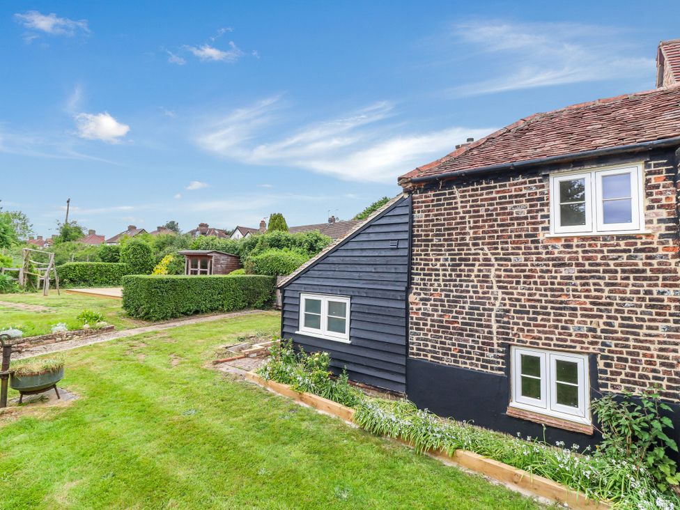 A garden with a house and playground at Tuffs Farm Cottage 1 in Kings Langley