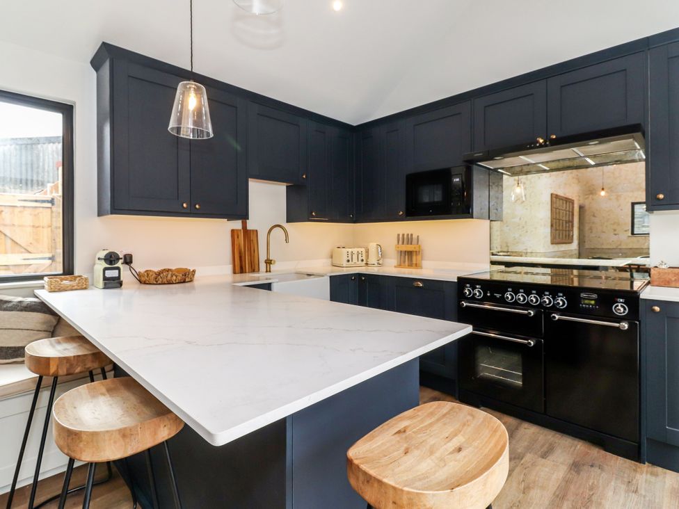 A kitchen with dark cabinets and a marble countertop at Tuffs Farm Cottage 2 Kings Langley