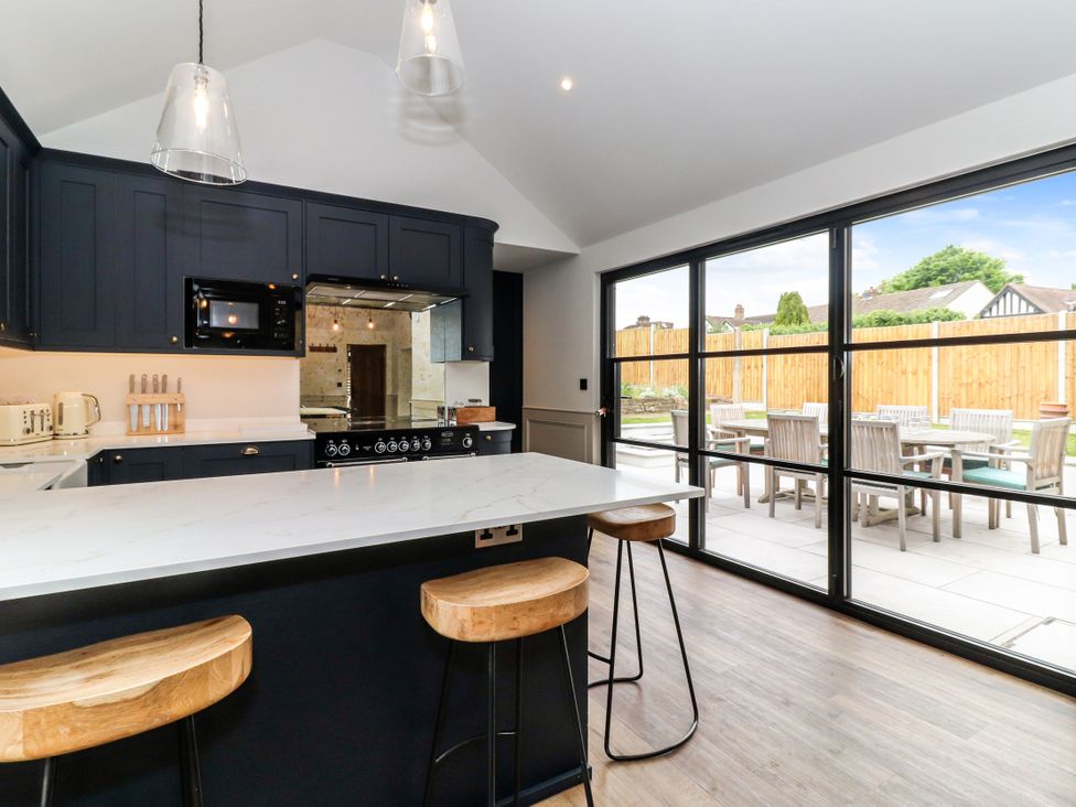 A kitchen with bar stools and kitchen island at Tuffs Farm Cottage 2 in Kings Langley