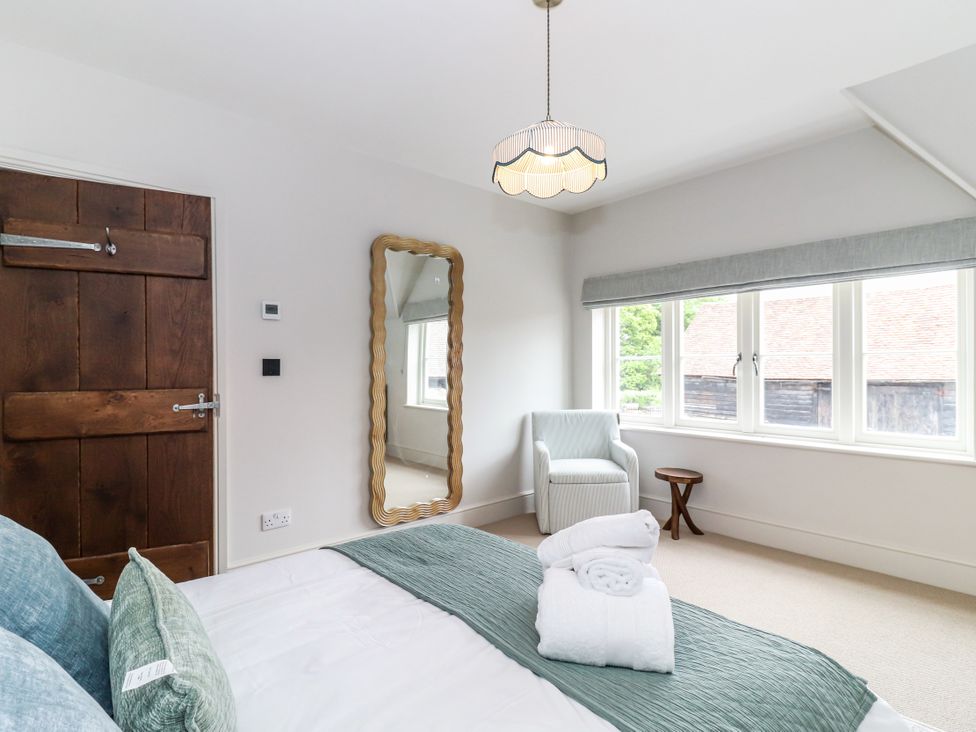 A bedroom with a bed and mirror at Tuffs Farm Cottage 2 in Kings Langley