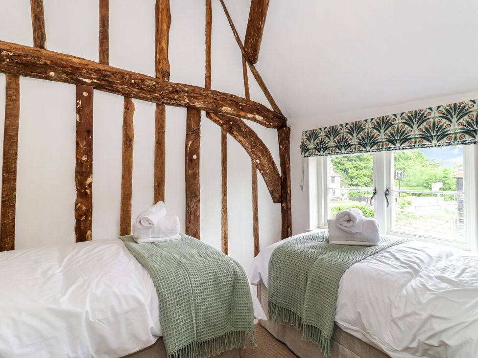 A bedroom with two single beds and a window at Tuffs Farm Cottage 2 in Kings Langley