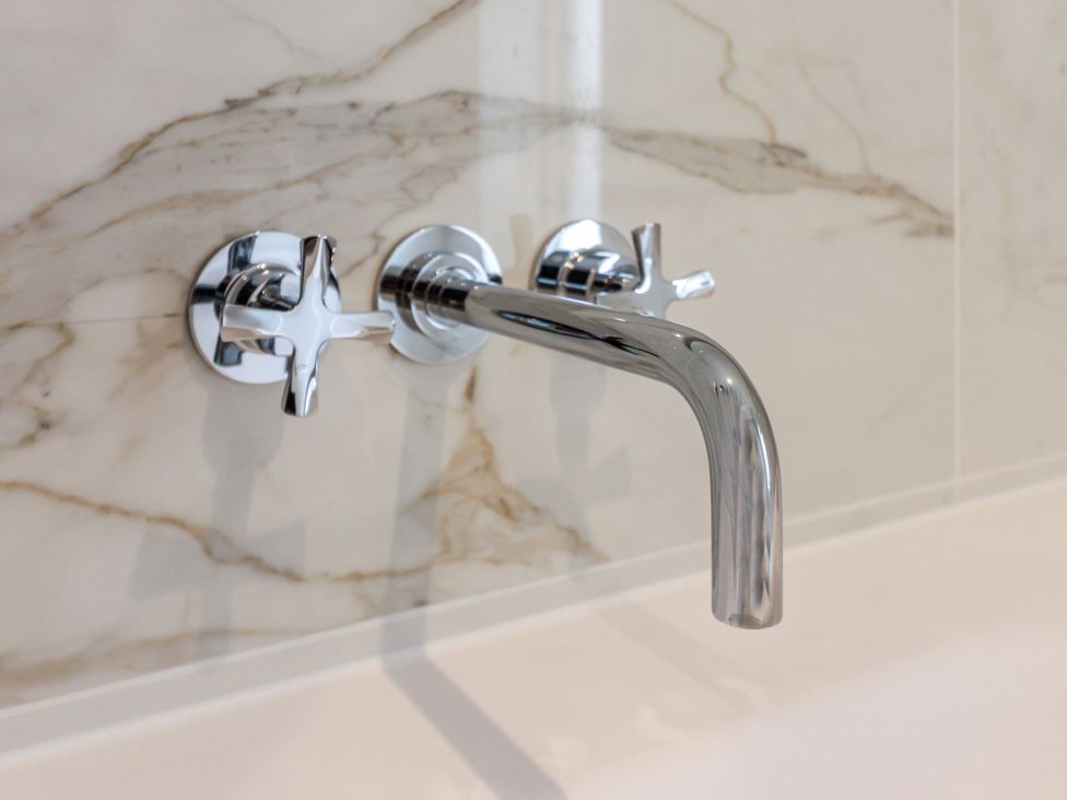 A wall-mounted faucet with hot and cold water taps at Tuffs Farm Cottage 2 in Kings Langley