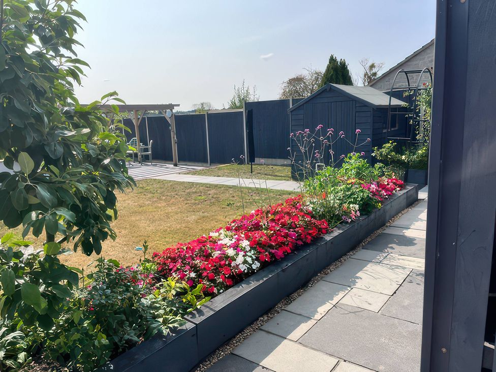 A garden with a flower bed and a shed at Curlew Cottage North Curry near Taunton