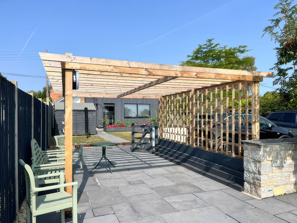 An outdoor area with a pergola, table, and chairs at Curlew Cottage near Taunton