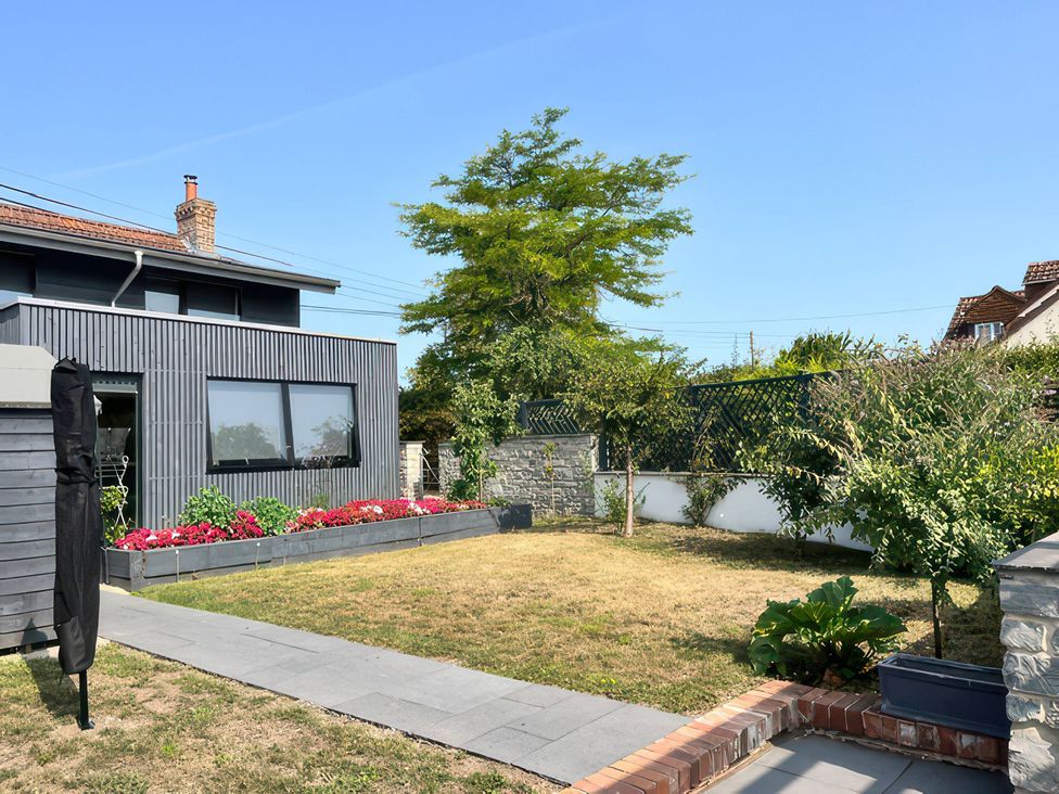 A garden with a house and flower bed at Curlew Cottage in North Curry near Taunton