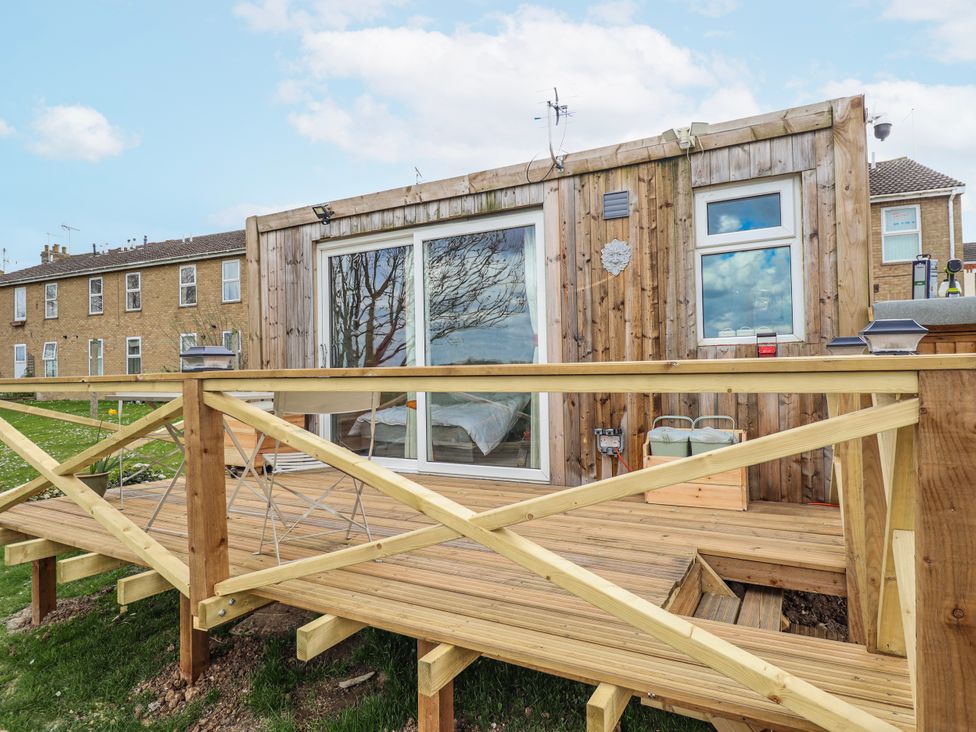 An outdoor area with a wooden deck and windows at Riverside Cabin in Peterborough