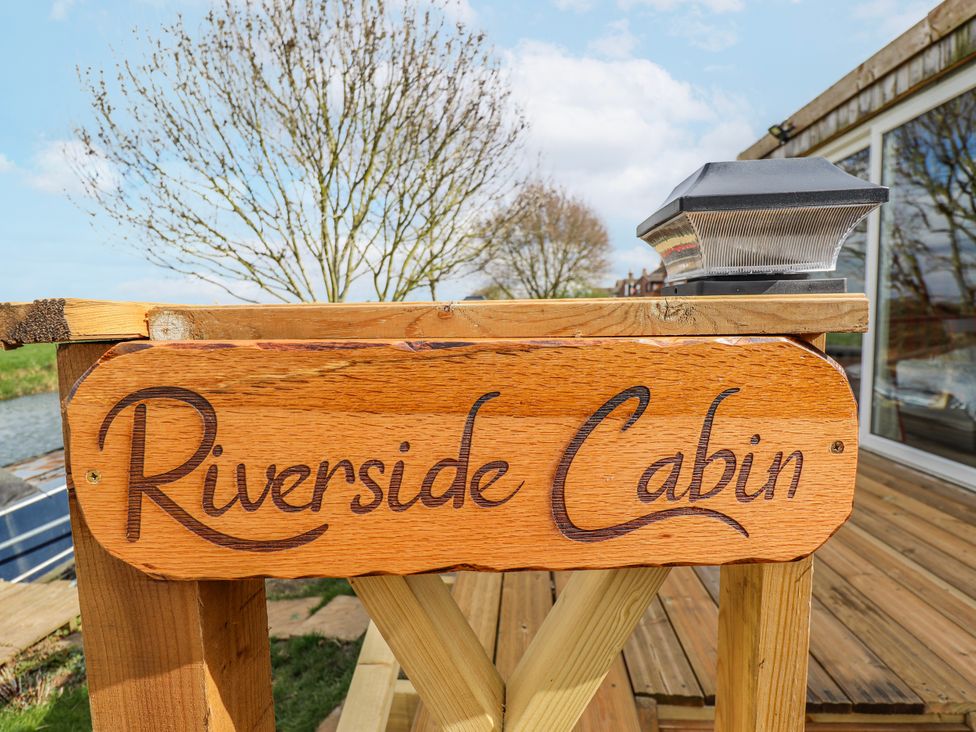 A wooden sign with the text Riverside Cabin at Riverside Cabin in Peterborough