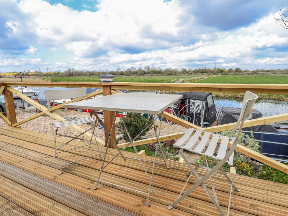 An outdoor area with a table and chair overlooking a river at Riverside Cabin in Peterborough