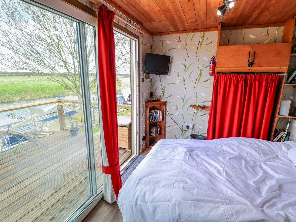 A bedroom with a bed and a television at Riverside Cabin in Peterborough