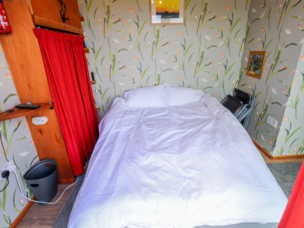 A bedroom with a bed and decorative wall at Riverside Cabin in Peterborough
