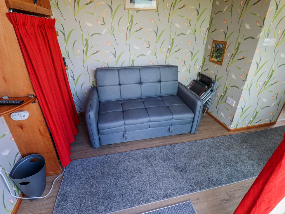 A snug with a sofa and a curtain at Riverside Cabin in Peterborough
