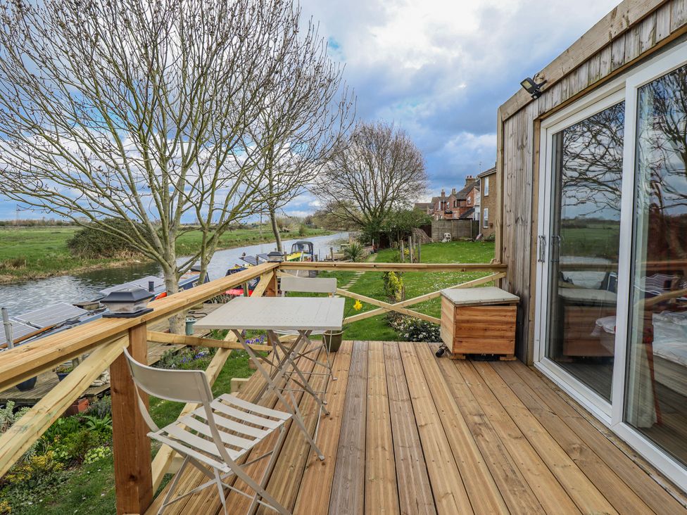 An outdoor area with a table and chairs overlooking a waterway at Riverside Cabin in Peterborough
