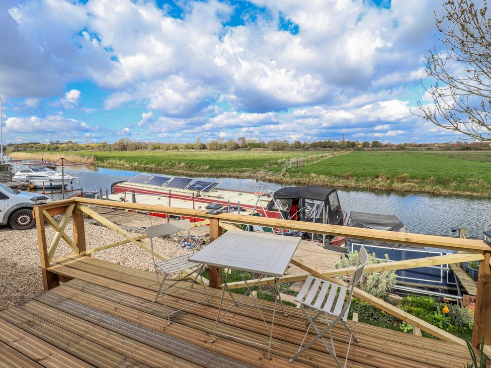 An outdoor deck with a table and chairs overlooking the river at Riverside Cabin in Peterborough