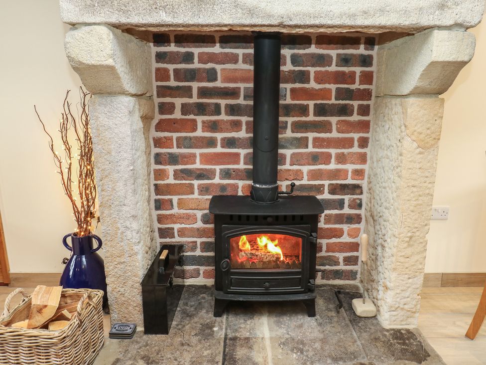 A wood stove with bricks in a living room at Moss Cottage in Cragg Vale