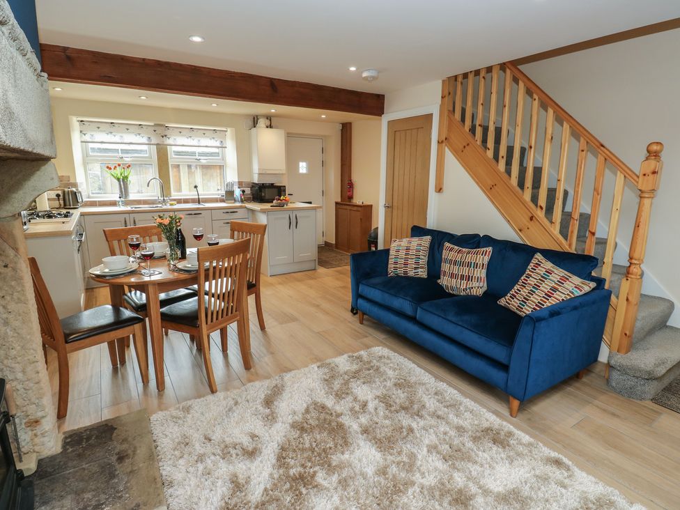 A living room with a dining area and a staircase at Moss Cottage in Cragg Vale