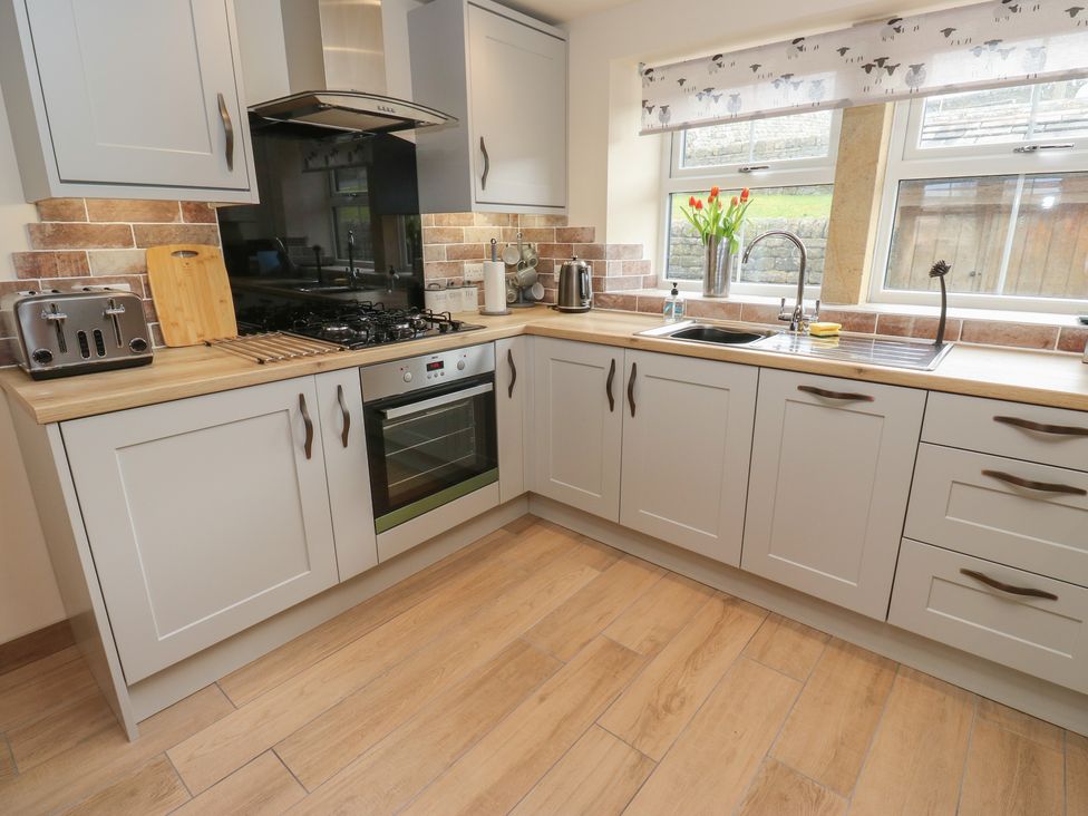 A kitchen with a sink and gas stove at Moss Cottage in Cragg Vale
