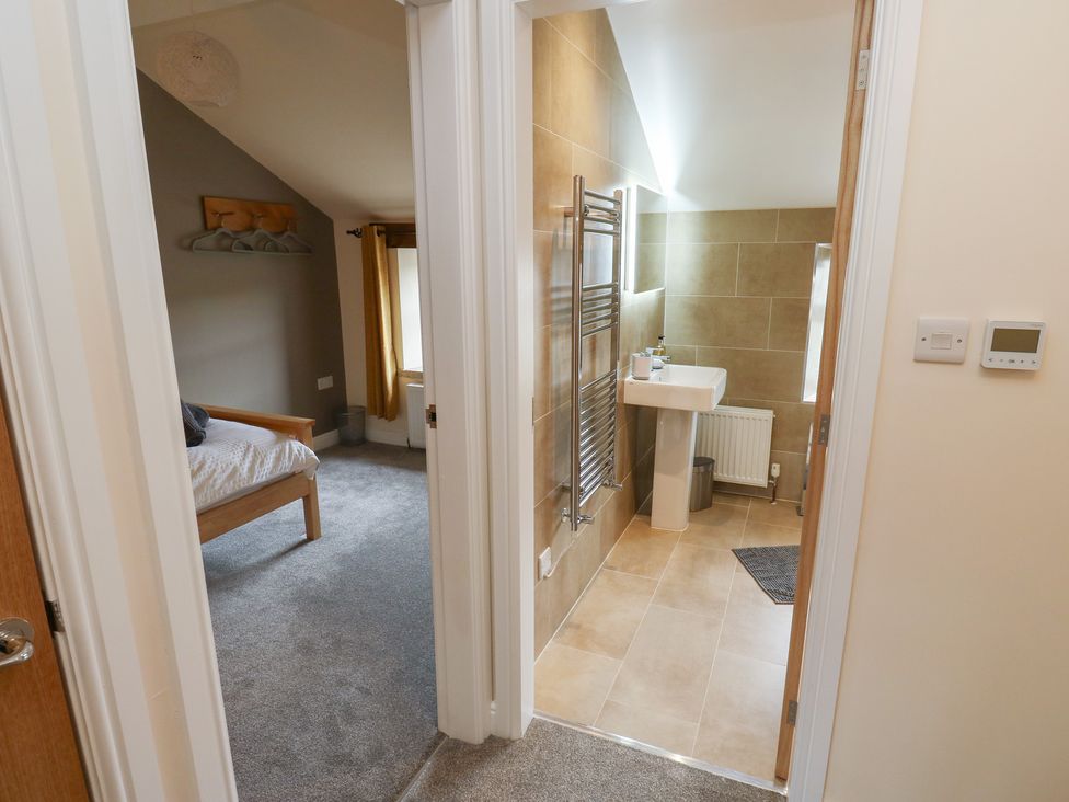 A bedroom with a bed and a bathroom with a sink at Moss Cottage in Cragg Vale