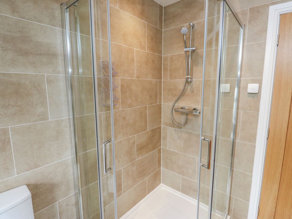 A shower enclosure with glass doors and a toilet at Moss Cottage in Cragg Vale
