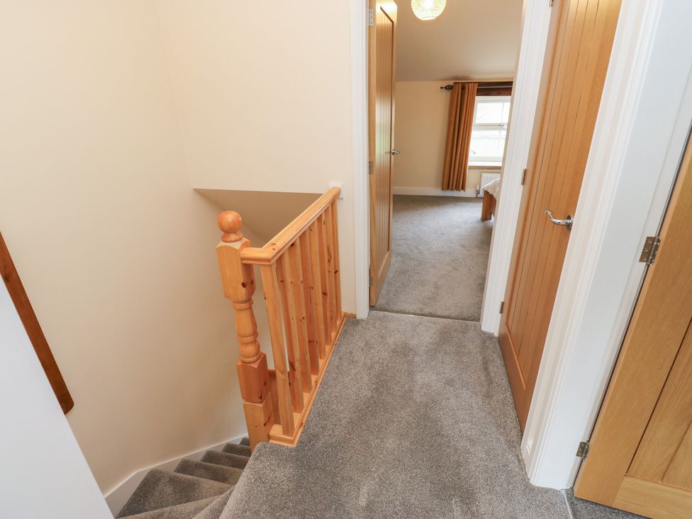 A staircase and hallway with doors at Moss Cottage in Cragg Vale
