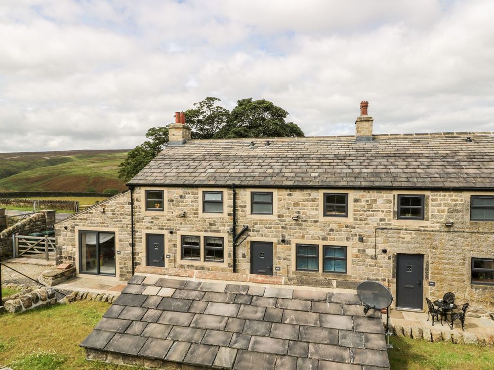 An outdoor view of a stone house with windows and doors at Moss Cottage in Cragg Vale