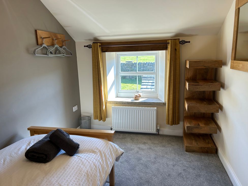 A bedroom with a bed and window at Moss Cottage in Cragg Vale