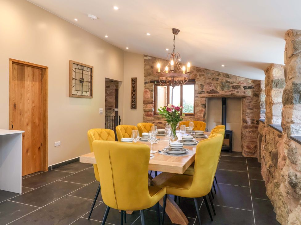 A dining room with a large table and yellow chairs at Heathmoor in Horrabridge