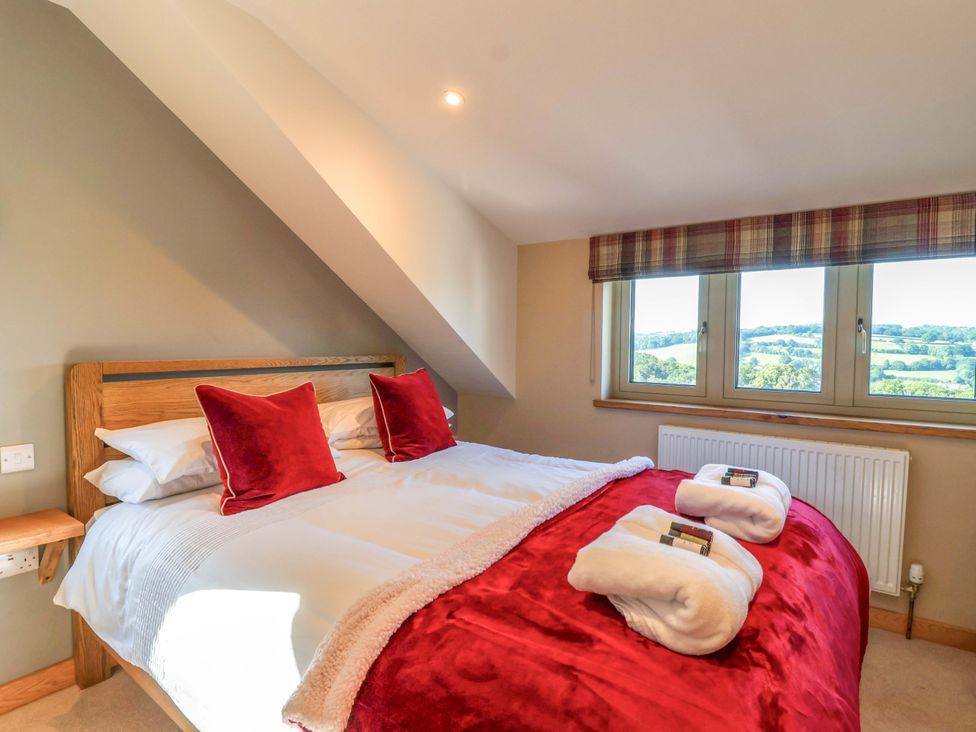 A bedroom with a bed and windows at Heathmoor in Horrabridge