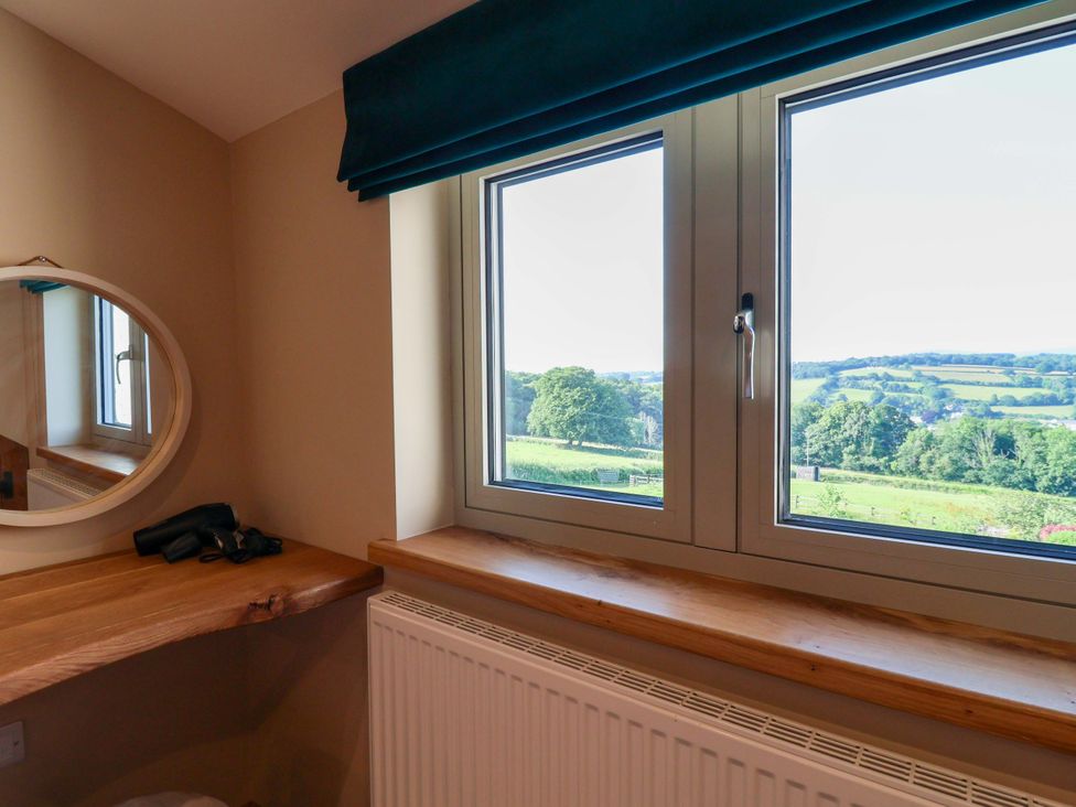 A bedroom with a window and mirror view at Heathmoor in Horrabridge