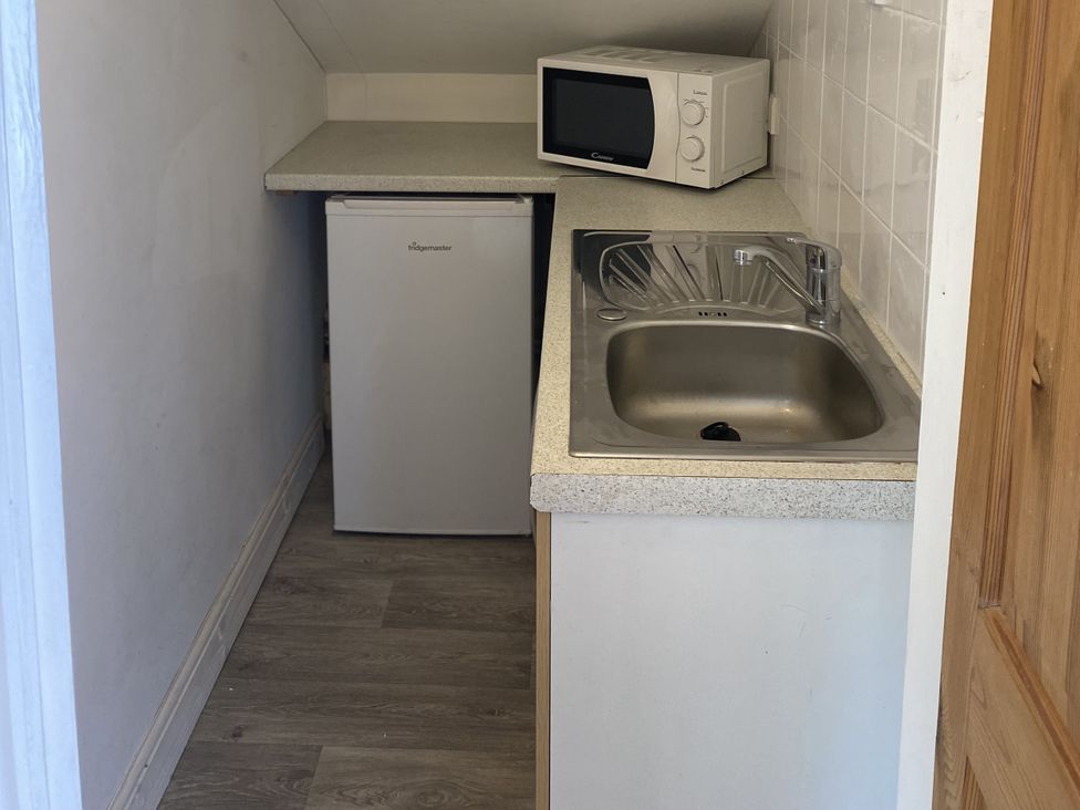 A compact kitchen area with a sink, refrigerator and microwave at Old Forge Apartment in Wolverly