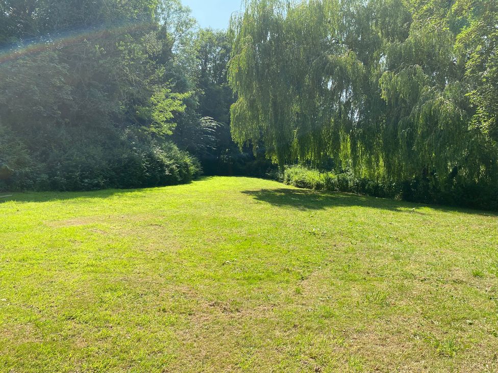 A grassy area with a willow tree at Old Forge Apartment Cookley