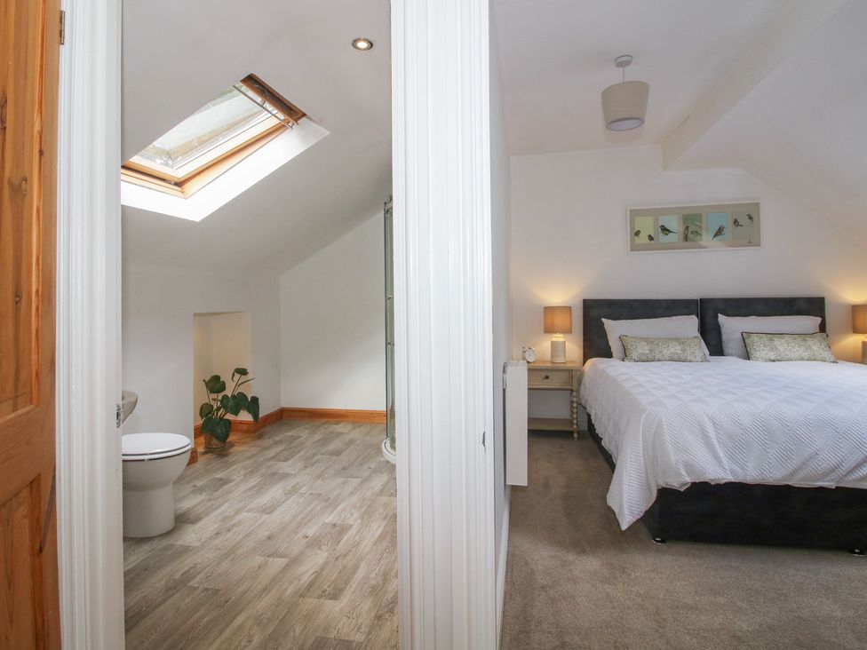 A bedroom with bed and nightstand beside a bathroom with toilet and shower at Old Forge Apartment in Cookley